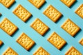 Pattern of golden baked rectangular crackers arranged diagonally on a vibrant blue background with soft shadows for a minimalist Royalty Free Stock Photo