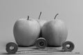 Pattern made of apple fruits near blue and yellow tape measures. Apples near measuring tape rolls on green background