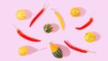 A pattern made of yellow and red hot chili peppers and yellow and green pumpkin on pastel pink background. Happy and healthy