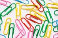 Pattern from multicolored paper clips scattered on white background. School office supplies paperwork documents organization