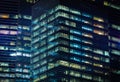 Pattern of office buildings windows illuminated at night. Lighting with Glass architecture facade design with reflection in urban