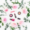 Pattern of pink rose flowers with eucalyptus branches and cosmetic: lipstick, shadows, mascara on white background. Flat lay, top Royalty Free Stock Photo