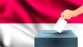 Male hand puts down a white sheet of paper with a mark as a symbol of a ballot paper against the background of the Indonesia flag,