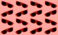 Pattern of red plastic sunglasses on background of pastel red color.