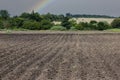 Pattern of rows in arable land against the background of a rainbow and a rainy sky Royalty Free Stock Photo