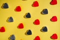 Pattern of rows of red and dark gray hearts on isolated yellow studio background. Crystals, glisten confetti Royalty Free Stock Photo