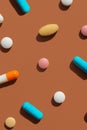 Pattern of several pills and tablets blue, pink, yellow and white colors on brown background. Creative tablets concept Royalty Free Stock Photo