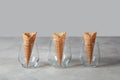 The pattern of wafer ice cream cones empty in the vases on a gray concrete table. Royalty Free Stock Photo