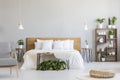 Patterned armchair and pouf in bright bedroom interior with wood