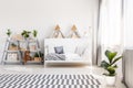 Patterned carpet and plant in white scandi bedroom interior with