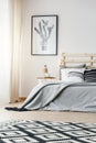 Patterned carpet and poster in grey simple bedroom interior with Royalty Free Stock Photo