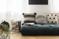 Patterned cushions on Futon in bright living room interior with blanket in the basket. Real photo Royalty Free Stock Photo