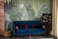 Patterned cushions on sofa next to wooden table and plant in dark apartment interior. Real photo Royalty Free Stock Photo