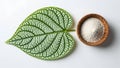 Patterned Green Leaf and Wooden Bowl with White Granules on White Background Royalty Free Stock Photo
