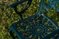 Patterned green metal chair stands on a green meadow on a sunny day