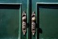 Patterned metal door handles on green double-leaf doors. Royalty Free Stock Photo