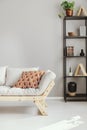 Scandinavian sofa next to shelf with different kind of accessories, real photo with copy space