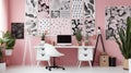 Patterned poster on table with computer monitor in Pink home office interior with plants Royalty Free Stock Photo