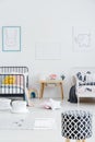 Patterned stool in bright kids bedroom interior with posters above black and white bed. Real photo Royalty Free Stock Photo