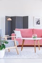 Patterned wooden armchair next to table and pink sofa in living