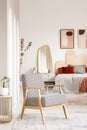 Patterned wooden armchair in pastel bedroom interior with poster