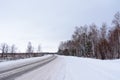 Patterns on the winter highway in the form of four straight lines. Snowy road on the background of snow-covered forest.