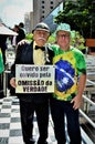 On Paulista avenue, an elderly man holds a sign that reads: `I want to be heard by omission of the truth`