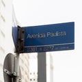 Paulista Avenue sign with mirrored buildings in the background during the day.