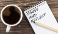 PAUSE AND REFLECT text on notebook with coffee on wooden background Royalty Free Stock Photo