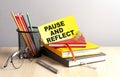 PAUSE AND REFLECT written on a sticky on notebooks