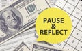 PAUSE AND REFLECT on yellow sticker with dollars and calculator