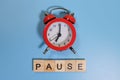 Pause word and alarm clock on blue background Royalty Free Stock Photo