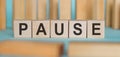 PAUSE word written on wooden blocks on light blue background