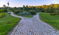 Paved cobblestone park alley leading to a large church with huge domes