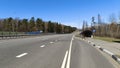 The paved motorway with markings is equipped with side and central metal fences, poles with lighting lights and an underground ped Royalty Free Stock Photo