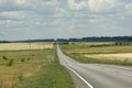 Paved road, highway with a white stripe, road among fields, poles, sunflower in summer Royalty Free Stock Photo