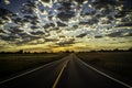 Paved Road leading into the Horizon as sun rays beam out of the clouds Royalty Free Stock Photo