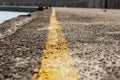 Paved road pier with a yellow stripe attracting attention and indicating the edge of the pier, focus in the middle of the line