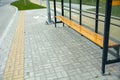 Pavement of a bus stop with a bench with grass in the background