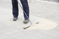 Pavement construction worker filling the block joints with sand using long broom