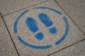 Pavement spray painted sign showing two blue feet marks inside a circle. Royalty Free Stock Photo