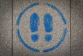 Pavement spray painted sign showing two blue feet marks inside a circle. Royalty Free Stock Photo