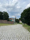 A pavement of stone tiles, a wall of boulders, an old city in the distance.