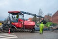 Paver laying asphalt on a new road with workers helping