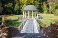 Pavilion in beautiful public garden park. White Gazebo forest view. Outdoor arbor with forged bridge, pond and background of a sum Royalty Free Stock Photo