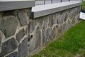 Paving made of irregular flat dark gray stones overgrown with grass irregular cracked look, retaining wall made of similar stones