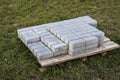 Paving slabs on a pallet prepared for installation on a green lawn. Paving the road with concrete paving slabs