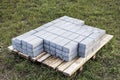 Paving slabs on a pallet prepared for installation on a green lawn. Paving the road with concrete paving slabs