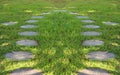 Paving stone tile walkway on green yard in the garden.