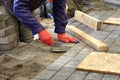 Paving the tiles on the sidewalk, the worker lay the tile, aligning it on the thread